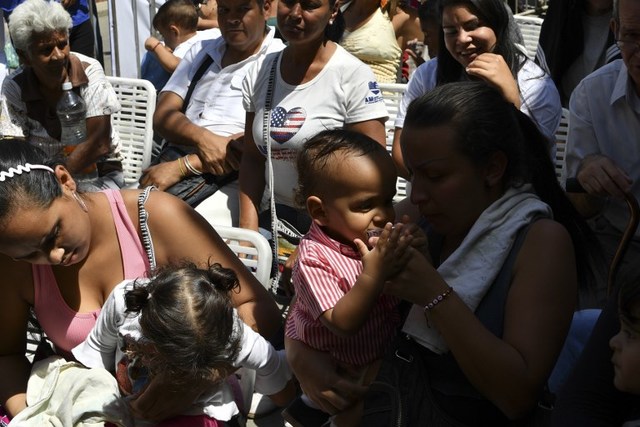 People wait for a chance to receive medical attention by volunteers of the Aid and Freedom Coalition movement during a medical attention camp in the Macarao neighbourhood in Caracas, on February 17, 2019. - Venezuelan opposition leader and self declared acting president Juan Guaido set a goal Sunday of enlisting a million volunteers within a week to confront a government blockade that has kept tons of humanitarian aid, most of it from the United States, from flowing into the country. (Photo by Yuri CORTEZ / AFP)