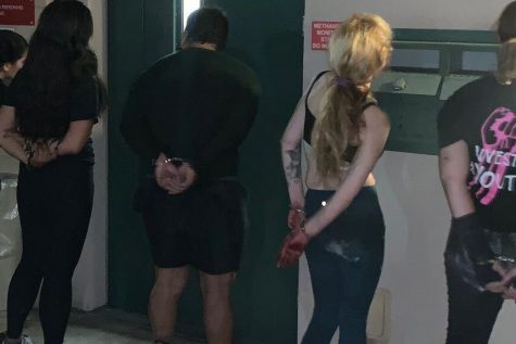 Pablo Unzueta, left, and Julianna Lacoste, middle, stand handcuffed outside the booking station after their arrest while covering a demonstration Sept. 8. Credit: Julianna Lacoste