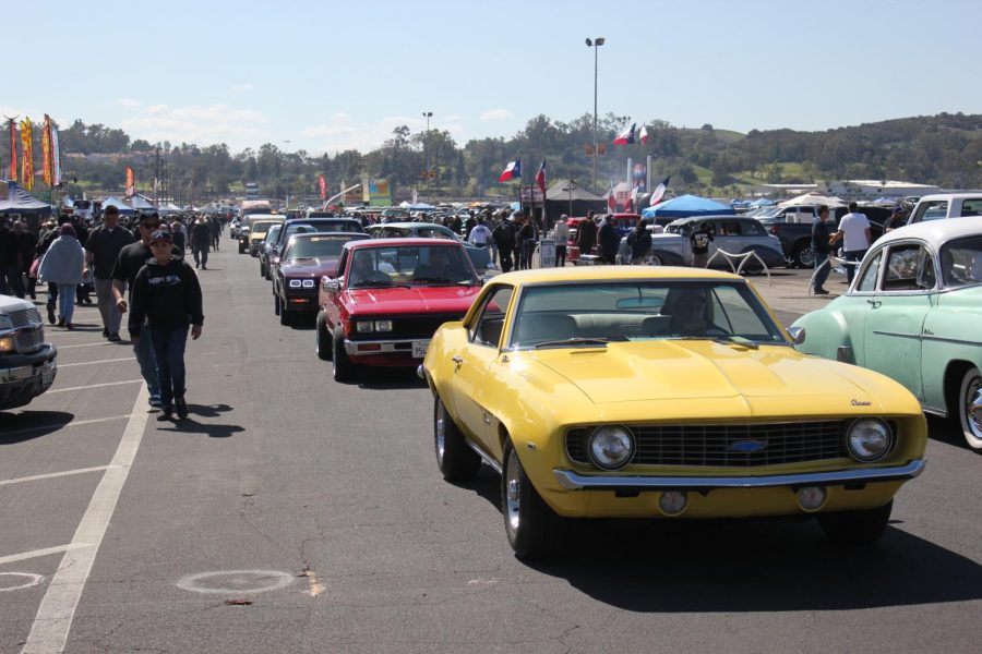 An iconic 1969 Chevy Camaro leads a seemingly endless line of classic cars.