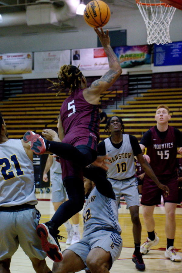 A sensational acrobatic attempt as sophomore shooting guard Jay Milner (5) attacks the defender trying to draw a foul. Though unsuccessful, it lead to an offensive rebound and free throws by freshman guard Nick Hopkins (10).