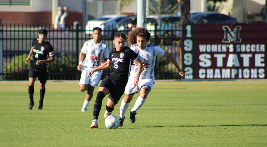 Freshman forward Hunter Devlin (5) keeping the ball away from the defender as he looks to advance the ball.