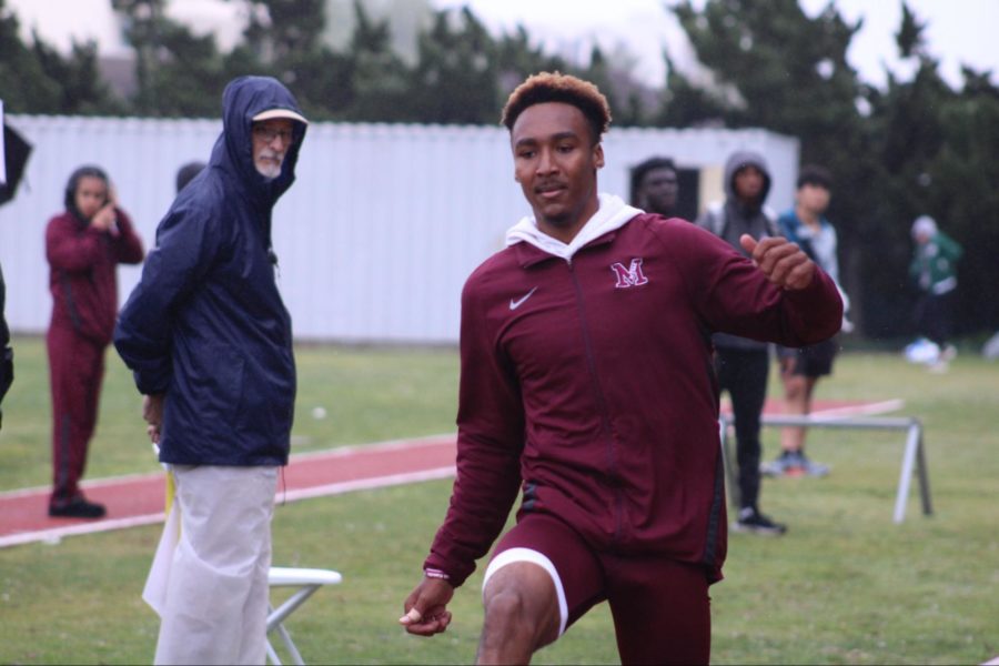 Sophomore Marcus Monroe Jr. warming up in the rain for the long jump event.