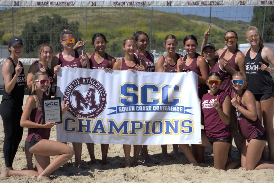 The+beach+volleyball+team+posing+with+their+South+Coast+Conference+champions+banner+as+their+regular+season+ends.