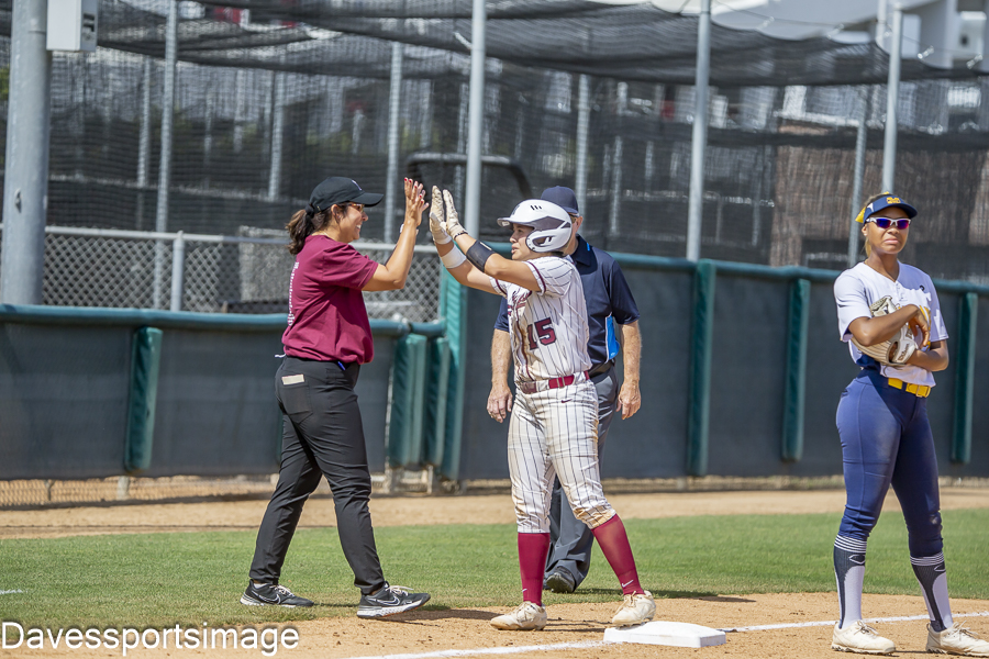 Sophomore catcher Celeste Cortez (15) high fiving her third base coach after reaching third base. Via Davesportsimage.