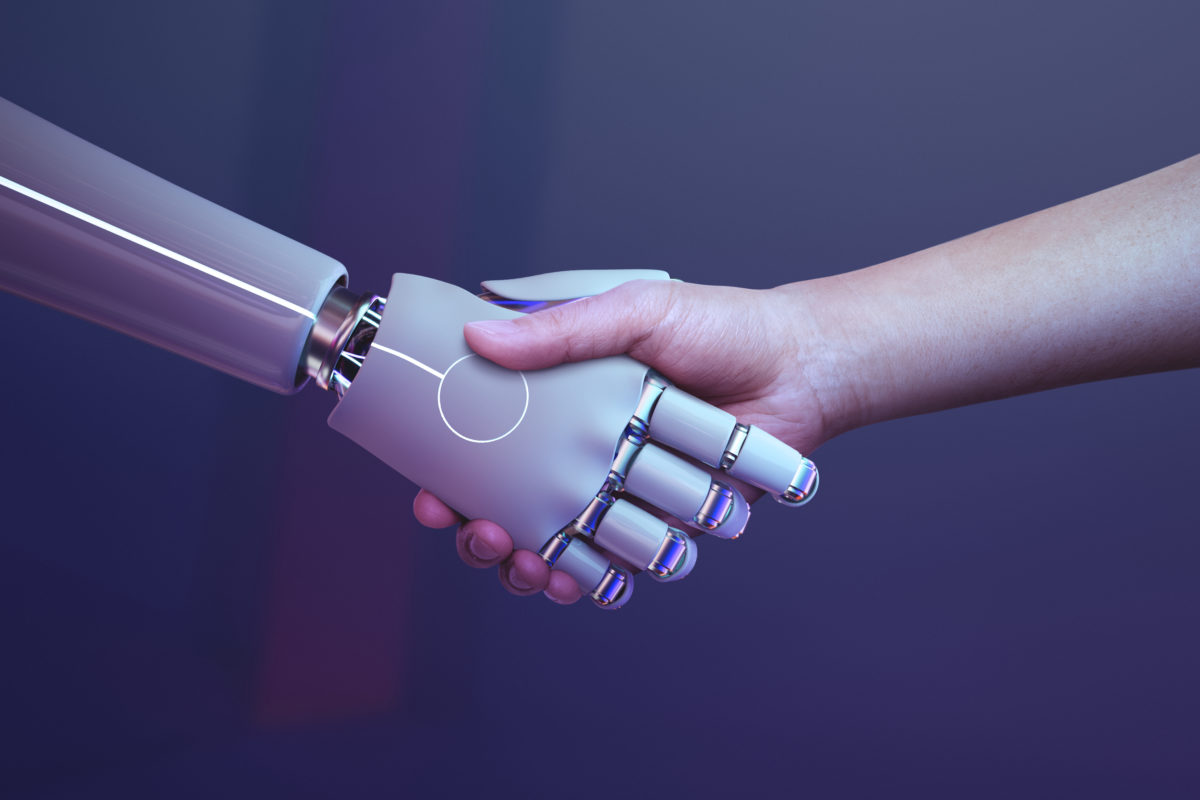 Human shaking hands with artificial intelligence represented as a robot hand.