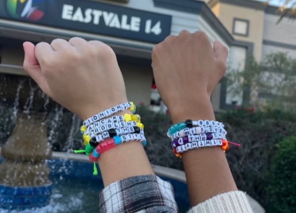 Swifties’ hands with friendship bracelets in front of the theater.