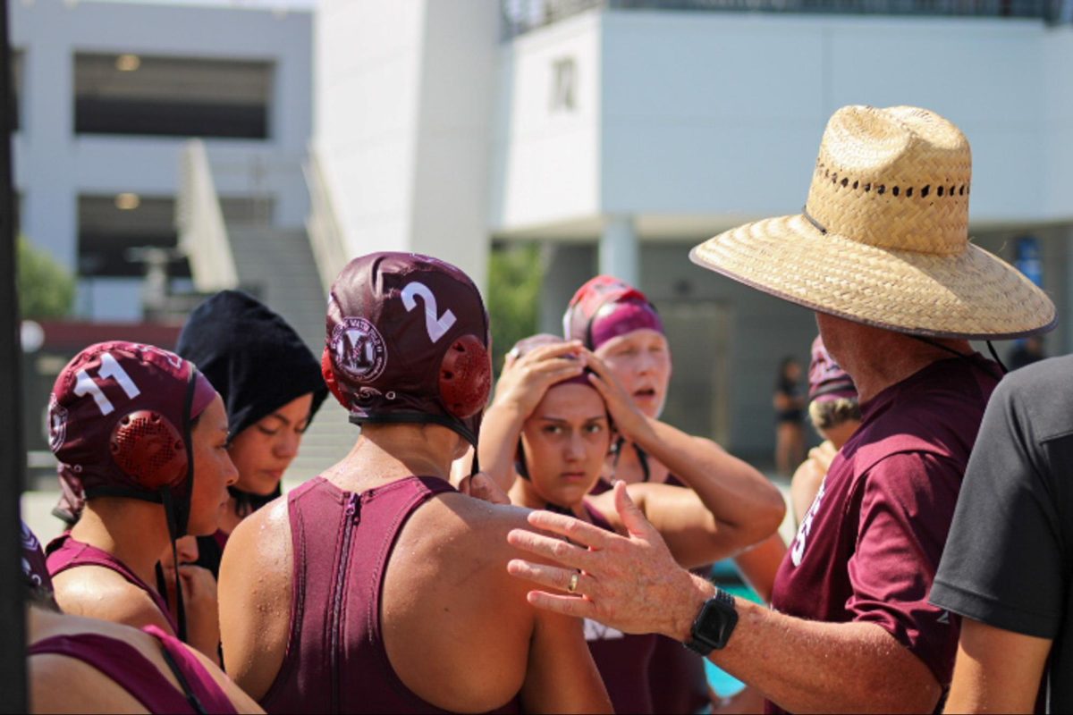 Head coach Chris Jackson strategizes with the Mt. SAC Women's water polo team while giving advice to freshman utility attacker Carolyn Kao (2). 