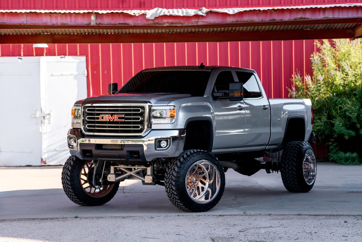 Silver GMC pickup truck with a lift kit on chrome wheels 