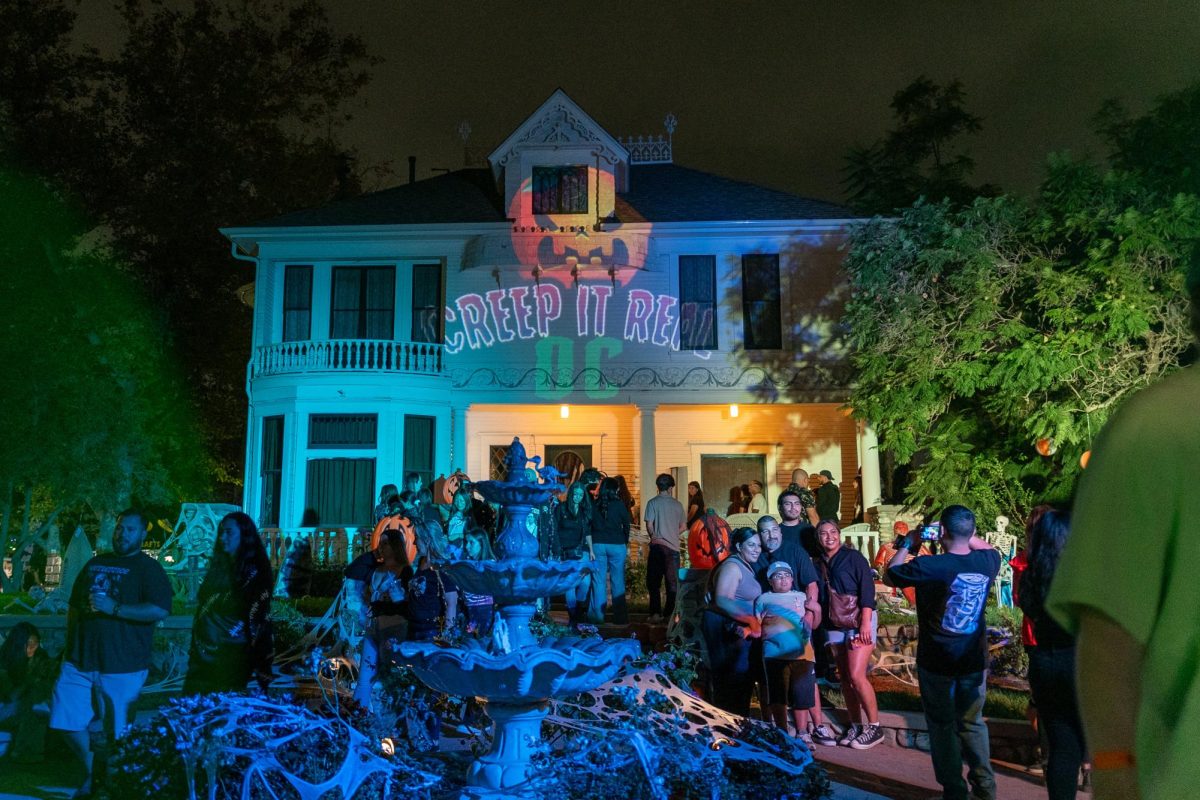 Guests gather outside the historic Kellogg House, illuminated with “Creep It Real OC” logo.