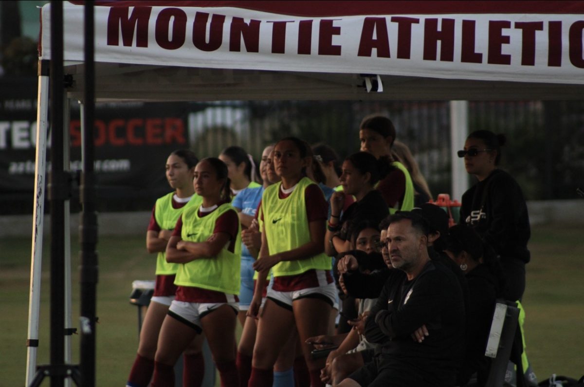 SAC coaches, staff and players watch from the sidelines as the game unfolds.