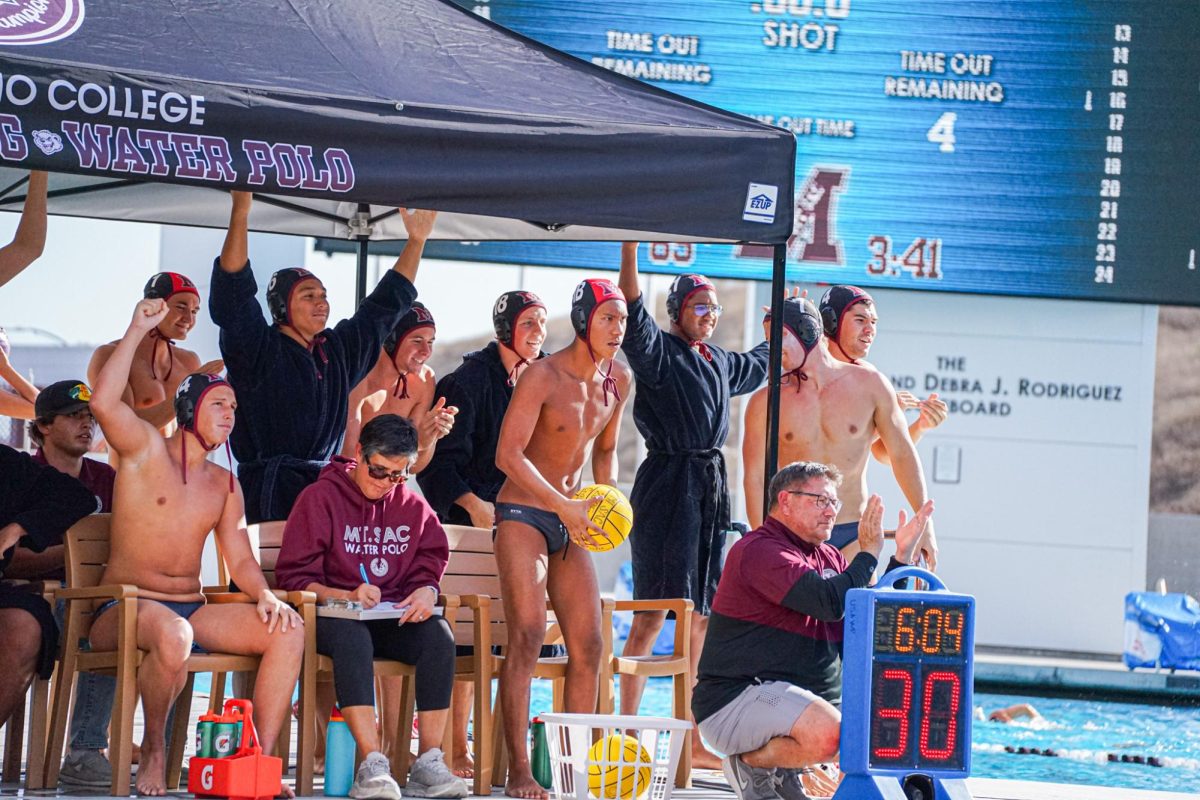Head coach Marc Ruh and the men’s water polo team cheering on SAC while assistant coach Lani Ruh gameplans 