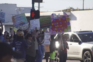 Protesters lining the street corner of Citrus and San Bernardino rallying with signs displaying different phrases that support immigration or Prop 50.