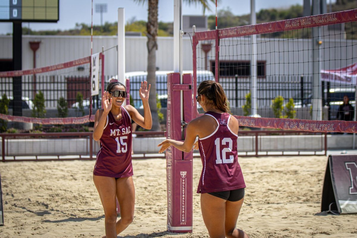 Eva Fisher (15) and Emma Carson (12) join in a high five after scoring their first point of the first set.   
